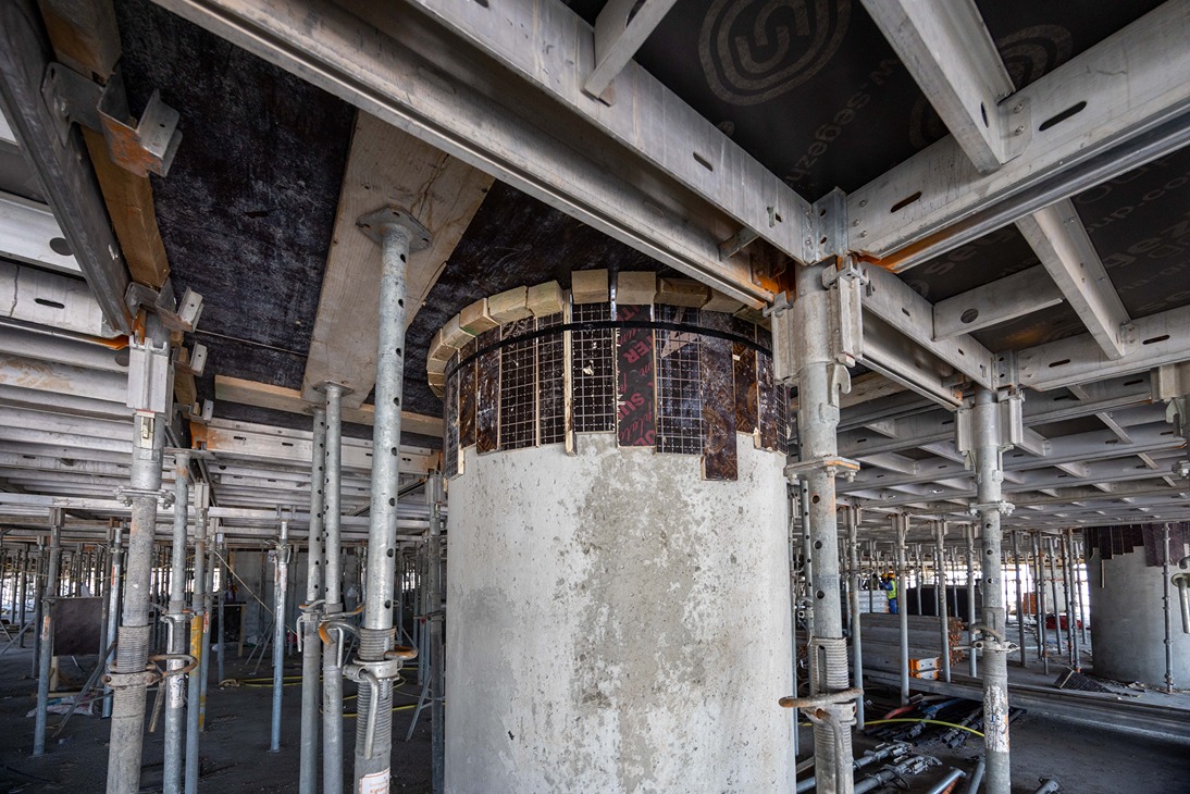 Beach Walk Iii By Imtiaz Construction site interior featuring concrete columns, scaffolding, and structural supports overhead.